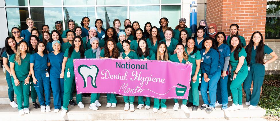 牙科卫生学生聚集在一起为一个国家牙科卫生月横幅的集团照片。