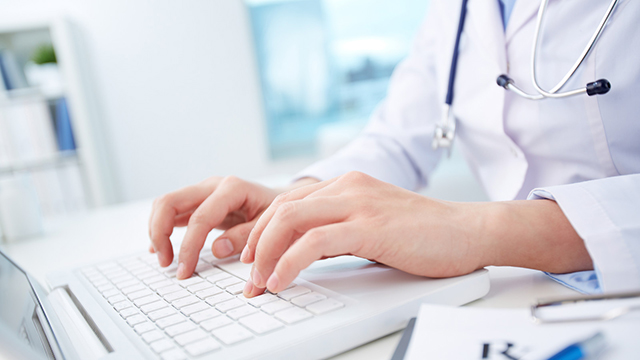 Doctor typing on a keyboard in a health care setting